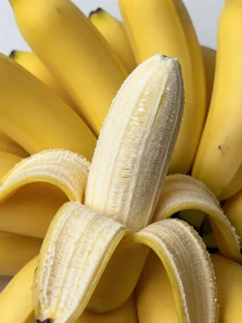 Plátano fresco entero y rebanado, en tazón y mesa rústica