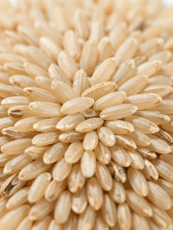 Granos de arroz integral crudo en tazón rústico sobre barra de cocina