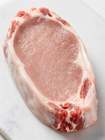 Trozos de carne de ternera fresca de color claro con especias en tabla de madera