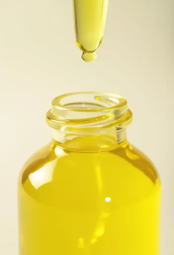 Aceite de limón en frasco pequeño junto a rodajas y ralladura de limón