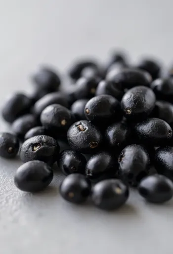 Frijoles negros brillantes, crudos y cocidos en tazón de cerámica y mesa rústica