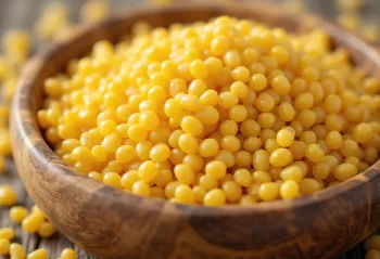 Mijo crudo de granos amarillentos en tazón de cerámica, sobre superficie de madera