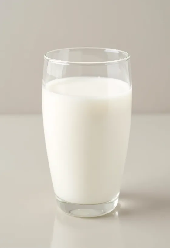 Vaso y jarra de leche fresca sobre barra de cocina limpia
