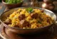Biryani de Res con rica carne de res especiada y arroz basmati, decorado con cilantro y menta fresca.