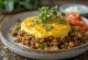 Bobotie vegetariano con lentejas y verduras, servido con eneldo fresco
