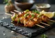 Yakitori clásico, pollo asado en brochetas, servido con ajonjolí y cebollín fresco
