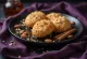 Galleta Melomakarona decorada con almendra, empapada en jarabe de miel, servida