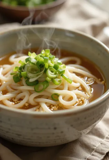 Kake udon servido en tazón con caldo dashi, cebollín fresco y ajonjolí
