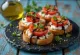 Bruschetta con jitomate, queso de cabra y albahaca fresca servida.