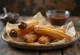 Churro relleno de exterior dorado y crujiente servido con crema de chocolate