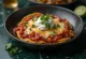 Chilaquiles rojos cubiertos con salsa de jitomate y chile, servidos con queso rallado y crema