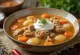 Ciorba de cerdo, caldo rico con carne y verduras servido con perejil fresco